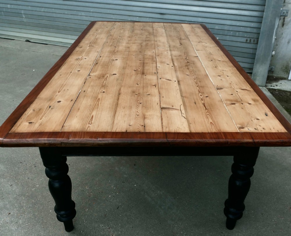 A large Victorian pine farmhouse dining table featuring a natural wood top with dark trim and a black painted base with four turned legs. View V