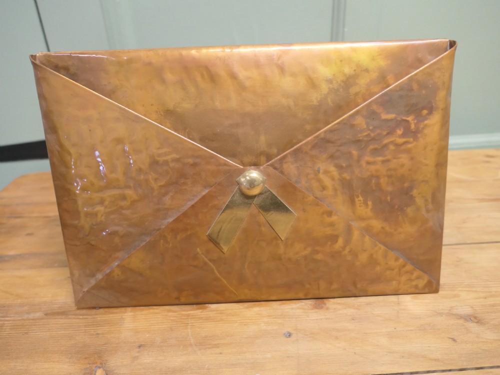 A beaten copper desk letter rack shaped like an envelope with a brass central stud detailing. View IV