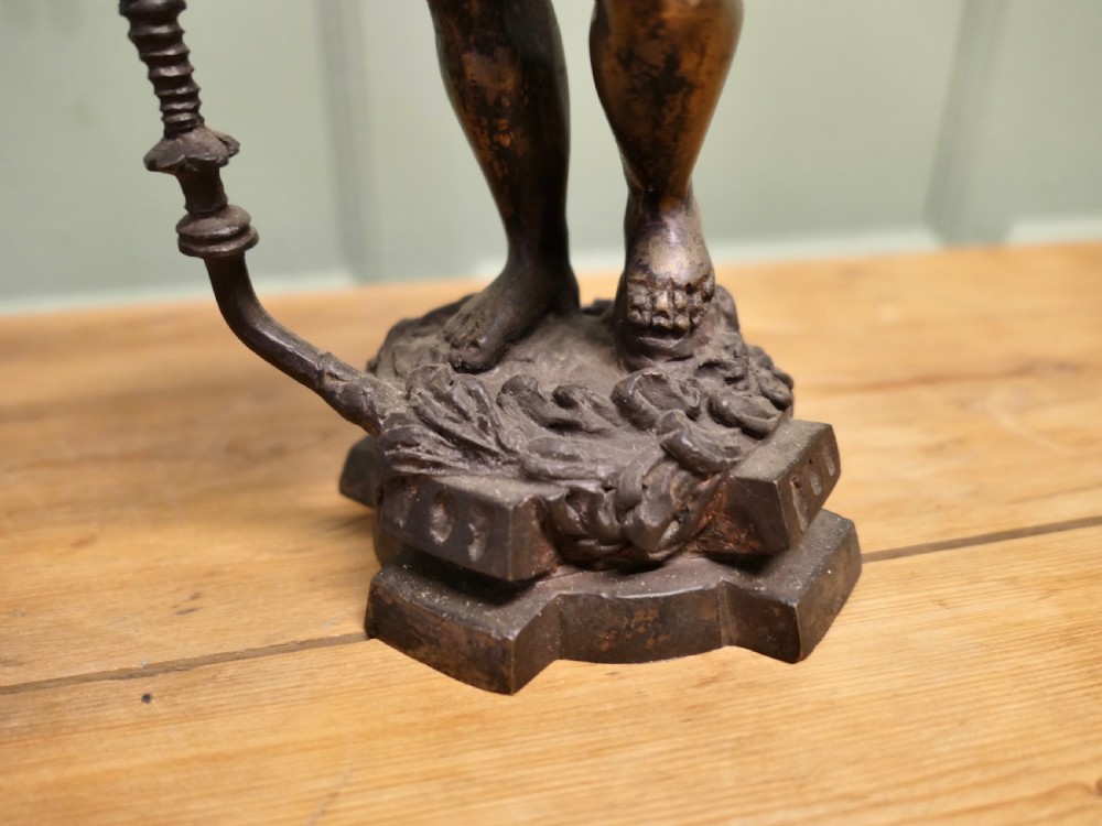 A pair of dark patinated cast brass figural candlesticks depicting standing figures in patterned tunics and turbans holding raised candle nozzles. View V