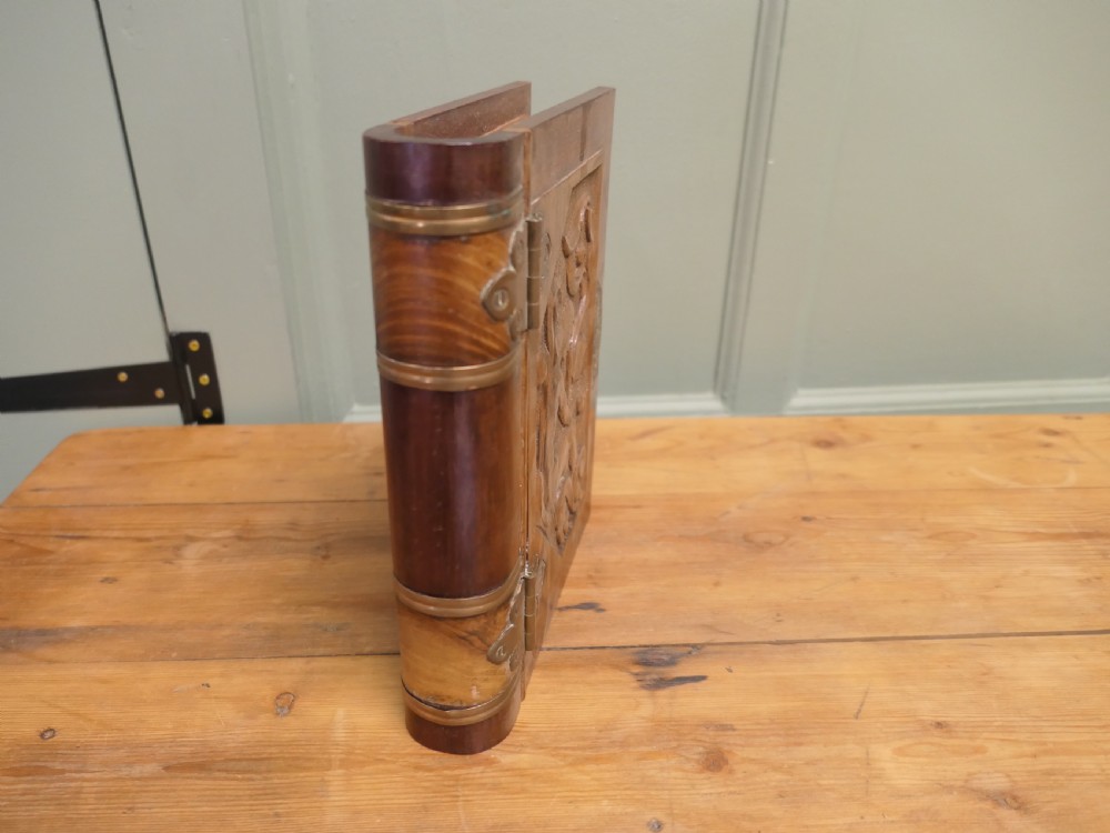 An Art Nouveau carved wooden book-shaped box with brass hinges featuring a relief carving of a seated figure surrounded by organic scrollwork. View III