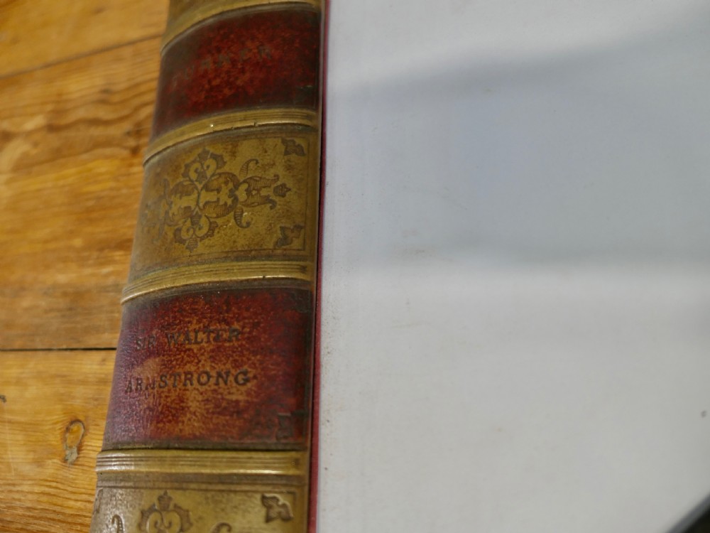 An antique leather desk blotter featuring faux book spine side borders with gold leaf tooling and a wooden ruler lying across the central pad. View III