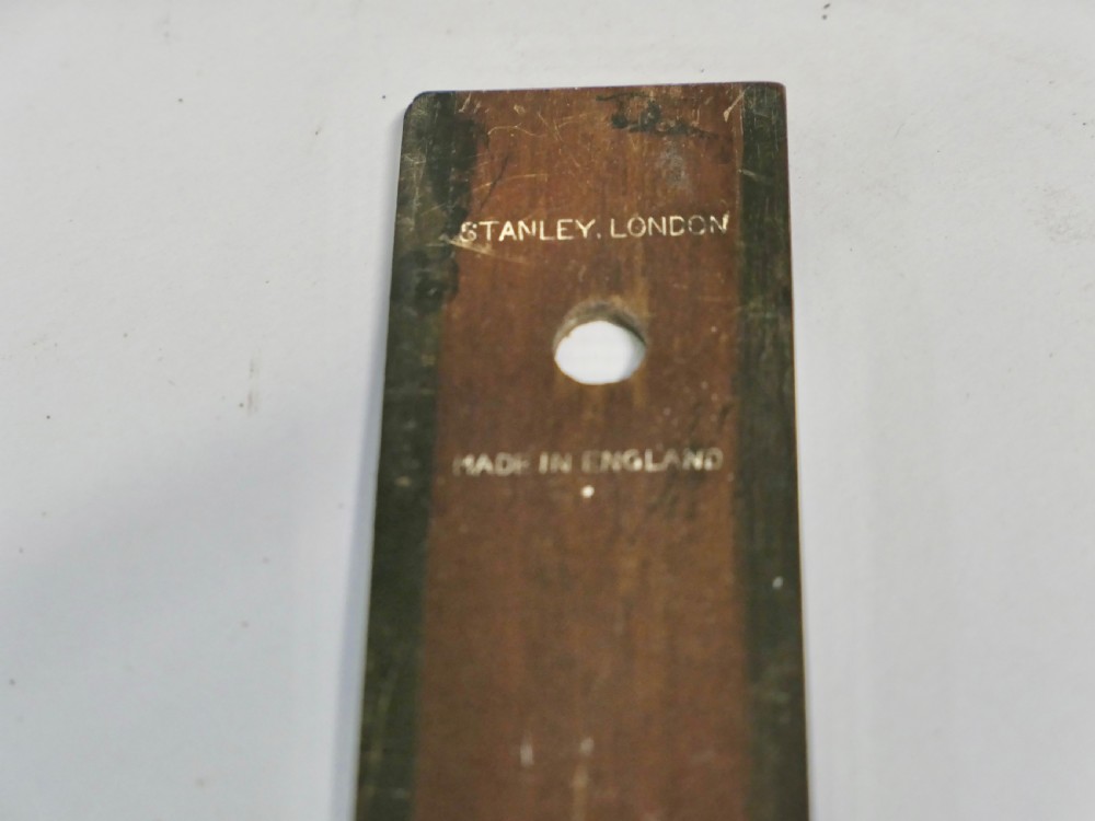 An antique leather desk blotter featuring faux book spine side borders with gold leaf tooling and a wooden ruler lying across the central pad. View VII