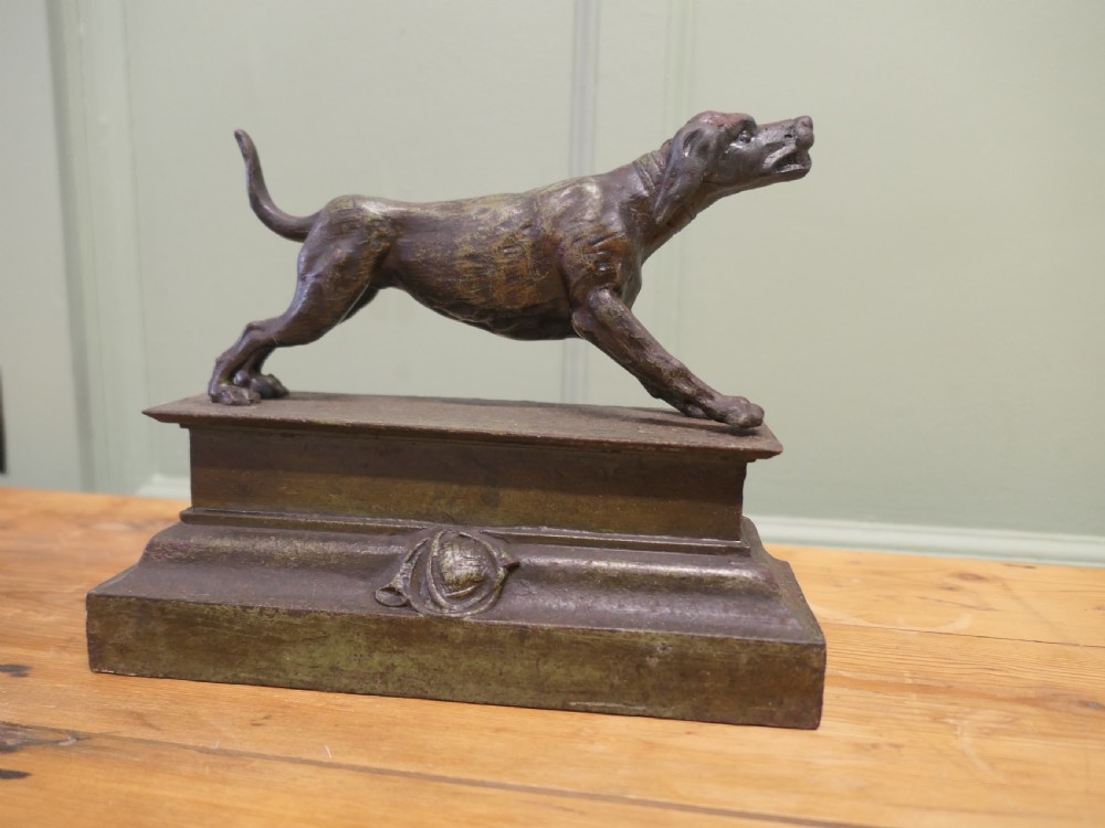 A patinated bronze sculpture of a hunting hound in a pointing posture mounted on a stepped rectangular plinth base.