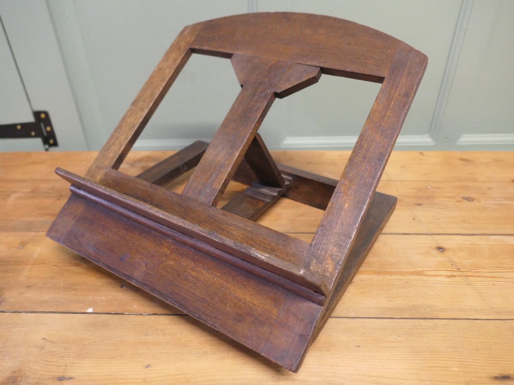 A solid dark oak sloped book rest featuring a wooden ledge and an adjustable hinged rear support.