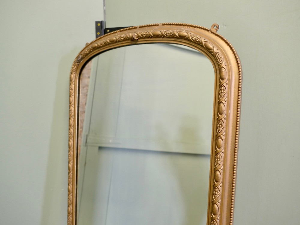 A tall 19th-century French Louis Philippe full-length mirror featuring a gold gilded frame with rounded top corners, floral moulding, and acanthus leaf corner details. View III