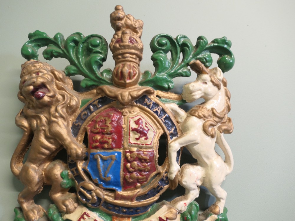 A painted cast iron wall plaque featuring the British Royal Coat of Arms with a gold lion and white unicorn supporting a quartered shield. View V
