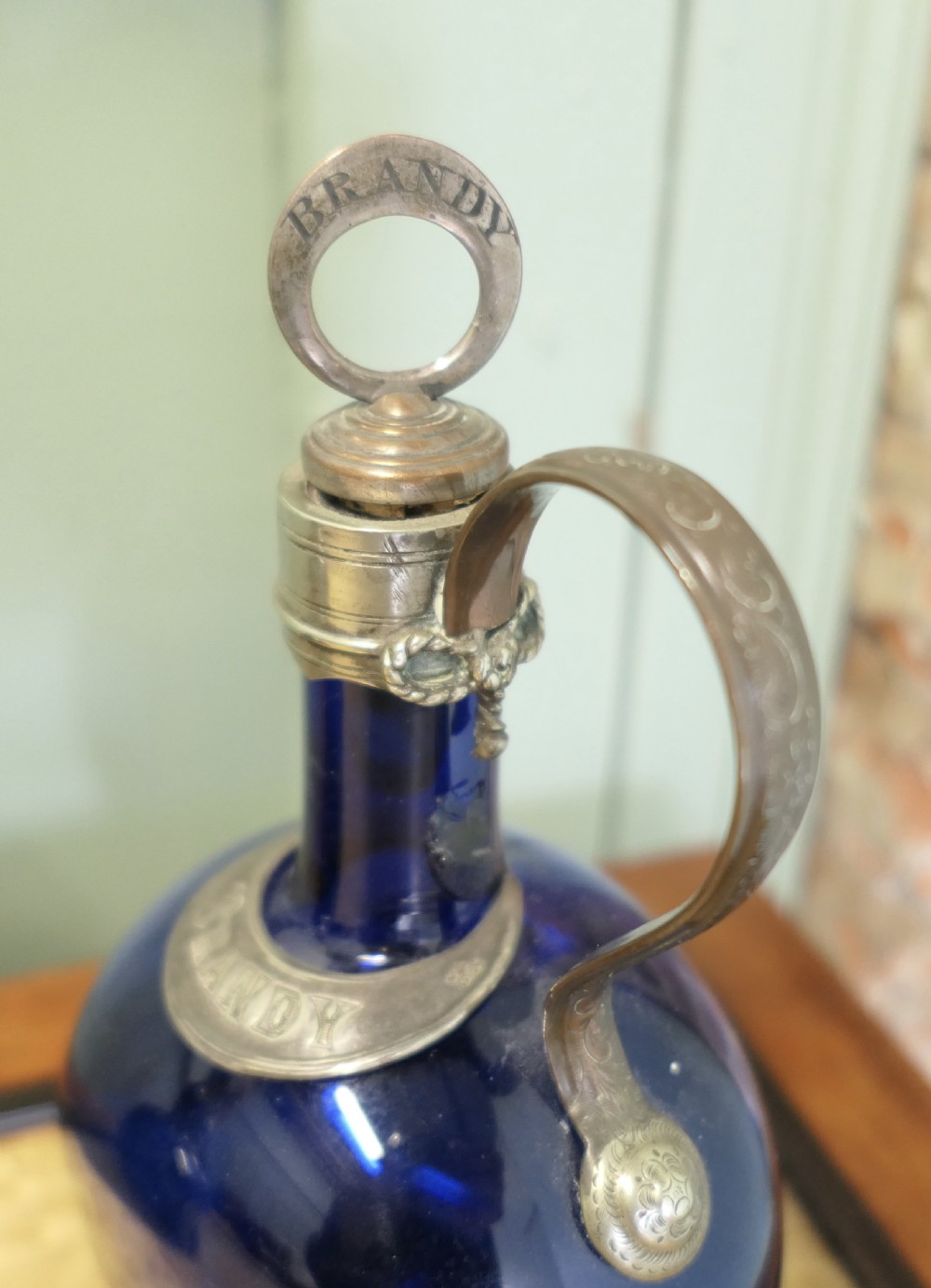 A collection of fifteen 19th-century Victorian coloured glass flagon decanters with metal spouts and stoppers arranged on a wooden surface. View II