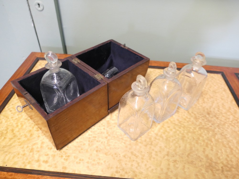 A 19th-century wooden decanter box featuring a curved top, warm brown grain, brass fittings, and a key inserted into the front lock. View III