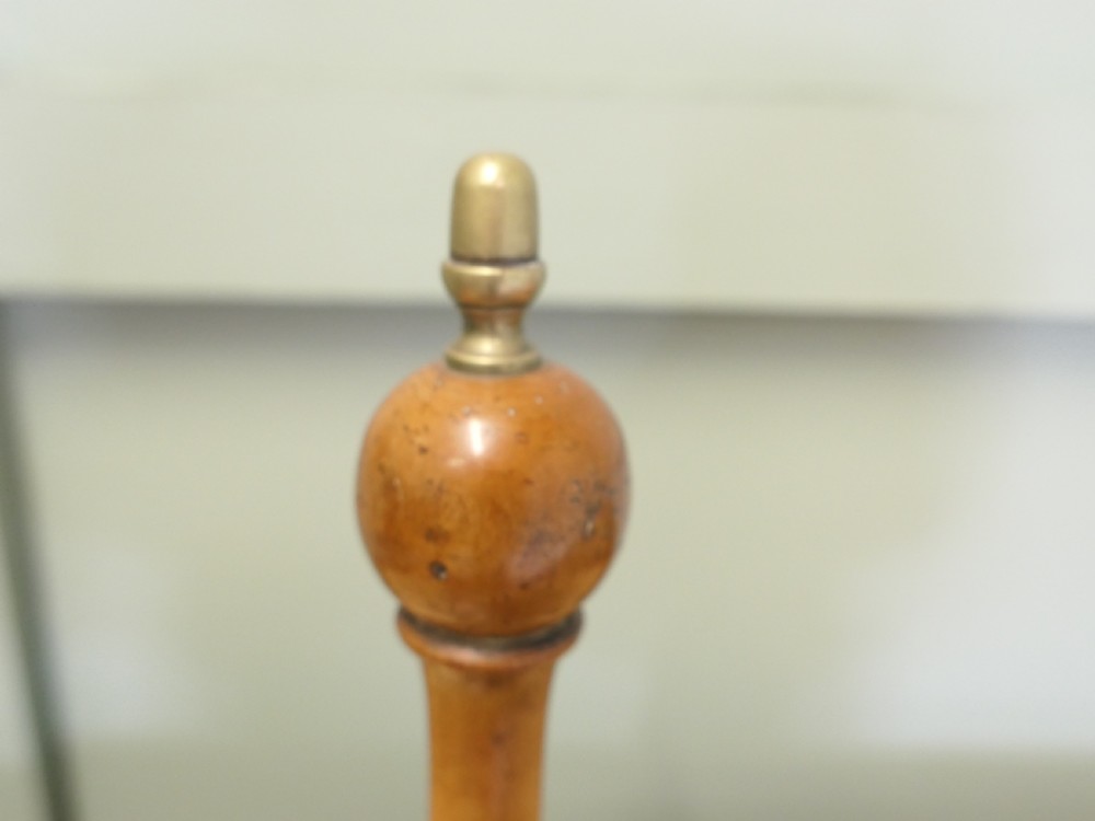An antique brass hand bell featuring a flared metal skirt, a turned wooden handle, and a brass finial top. View VI