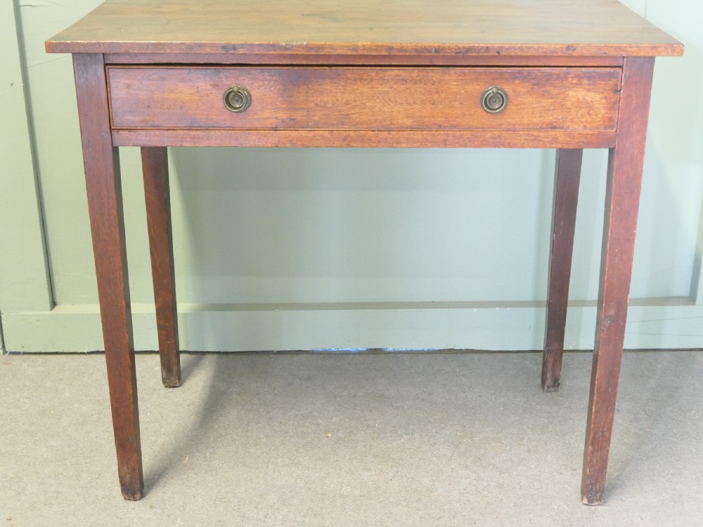 An early nineteenth-century warm brown oak writing table featuring a single frieze drawer with brass ring handles and four square tapered legs.
