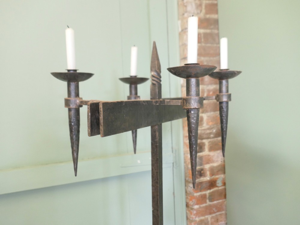 A tall wrought iron floor-standing candelabra featuring a twisted central stem, an arched four-legged base, and five candle holders on crossbars. View V