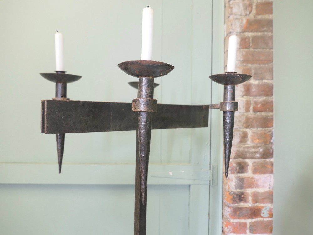 A tall wrought iron floor-standing candelabra featuring a twisted central stem, an arched four-legged base, and five candle holders on crossbars. View VII