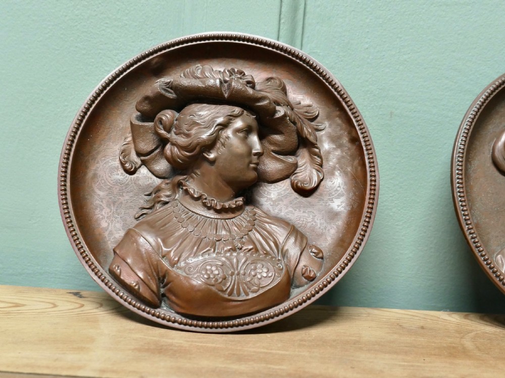 A pair of circular 19th-century copper wall plaques featuring raised relief portraits of a man and a woman in Renaissance attire within beaded borders. View IV