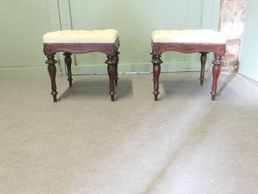 A pair of square deep-buttoned cream leather stools set on carved turned walnut legs with brass studding along the frames. View II