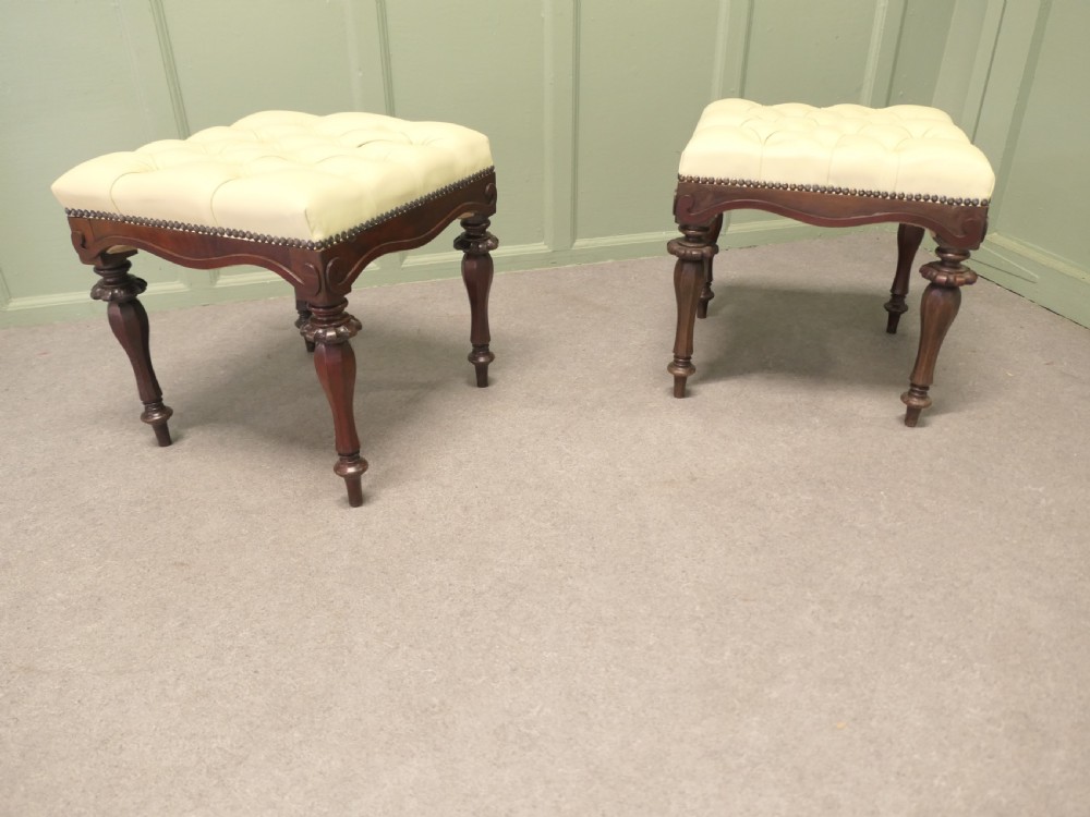 A pair of square deep-buttoned cream leather stools set on carved turned walnut legs with brass studding along the frames. View V