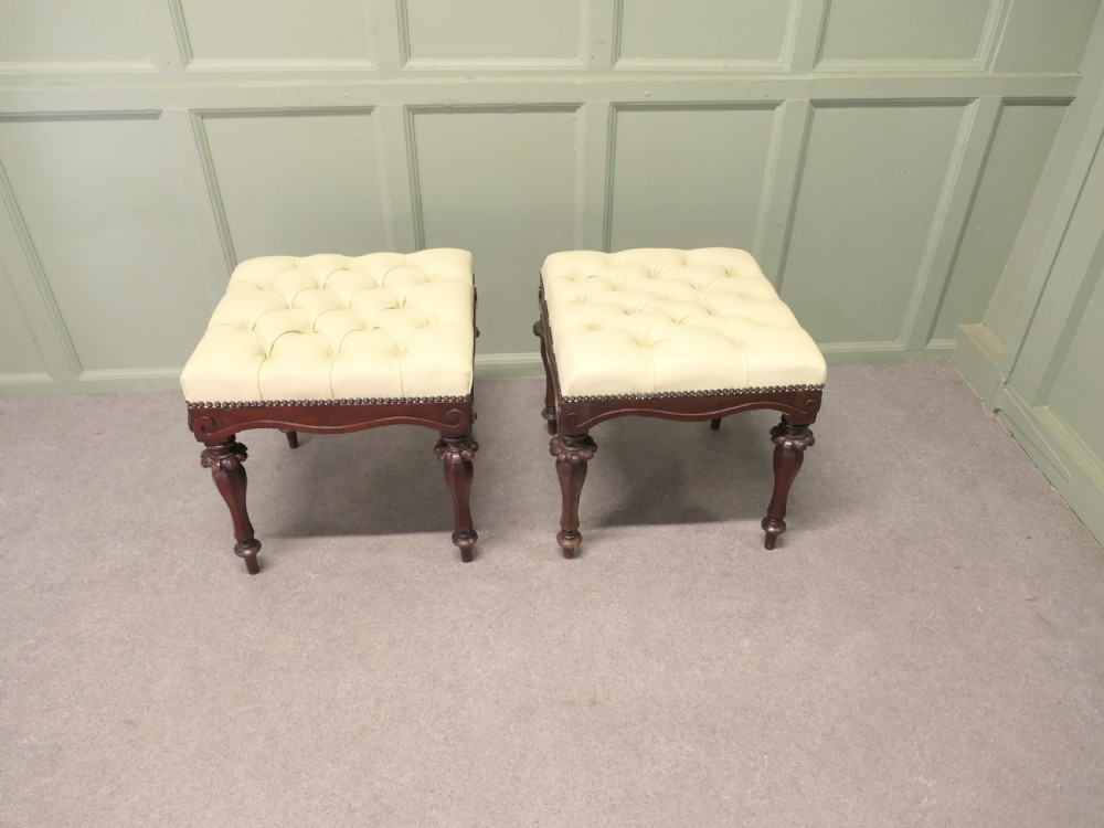 A pair of square deep-buttoned cream leather stools set on carved turned walnut legs with brass studding along the frames. View VI