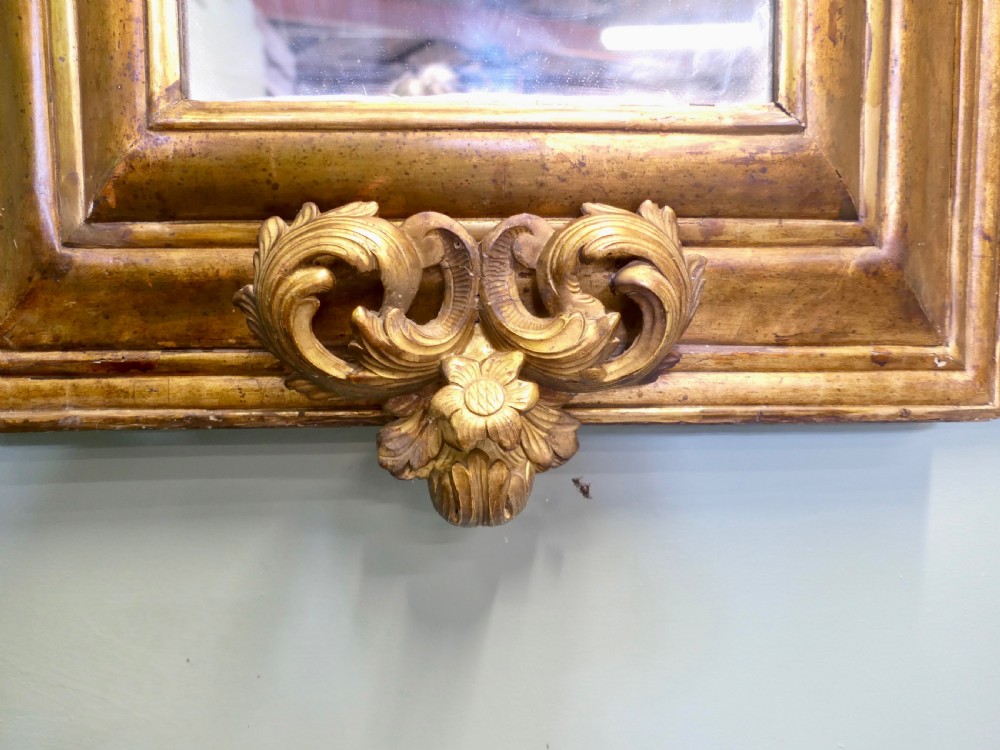 A 19th-century Regency carved giltwood wall mirror featuring a rectangular frame topped with a cresting of two cherubs flanking a flower basket. View VII
