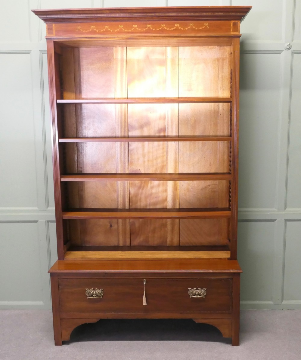 A tall Edwardian open walnut bookcase featuring an inlaid decorative frieze, four adjustable shelves, and a single wide base drawer with brass handles. View II