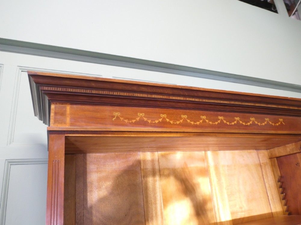 A tall Edwardian open walnut bookcase featuring an inlaid decorative frieze, four adjustable shelves, and a single wide base drawer with brass handles. View VII