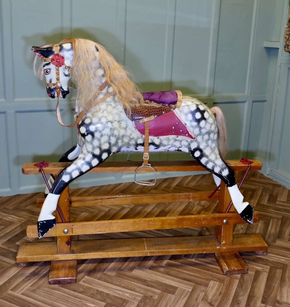 A large vintage dappled grey carved wooden rocking horse with blonde horsehair mane mounted on a pine safety stand.