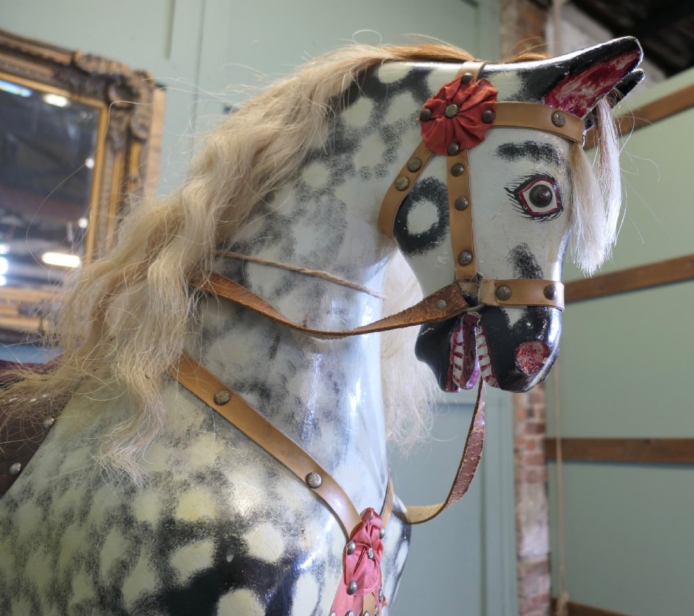 A large vintage dappled grey carved wooden rocking horse with blonde horsehair mane mounted on a pine safety stand. View II