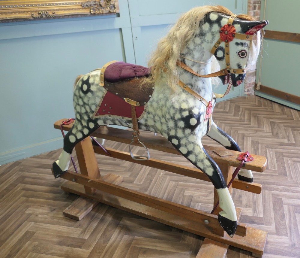 A large vintage dappled grey carved wooden rocking horse with blonde horsehair mane mounted on a pine safety stand. View V