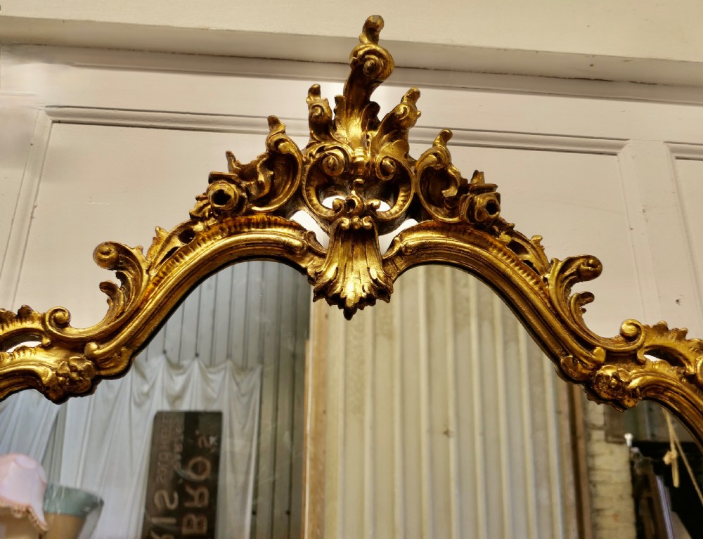 An ornate French Rococo style giltwood console table featuring a contoured white marble top beneath a matching gilded pier mirror with elaborate scroll carving. View III