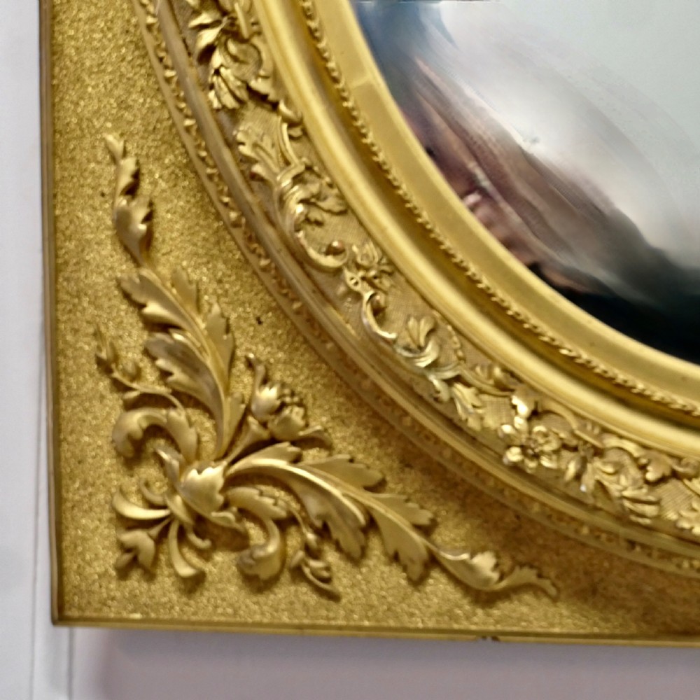 A rectangular gilded wood mirror frame featuring a central oval aperture with beaded detail and acanthus leaf corner mouldings. View VI