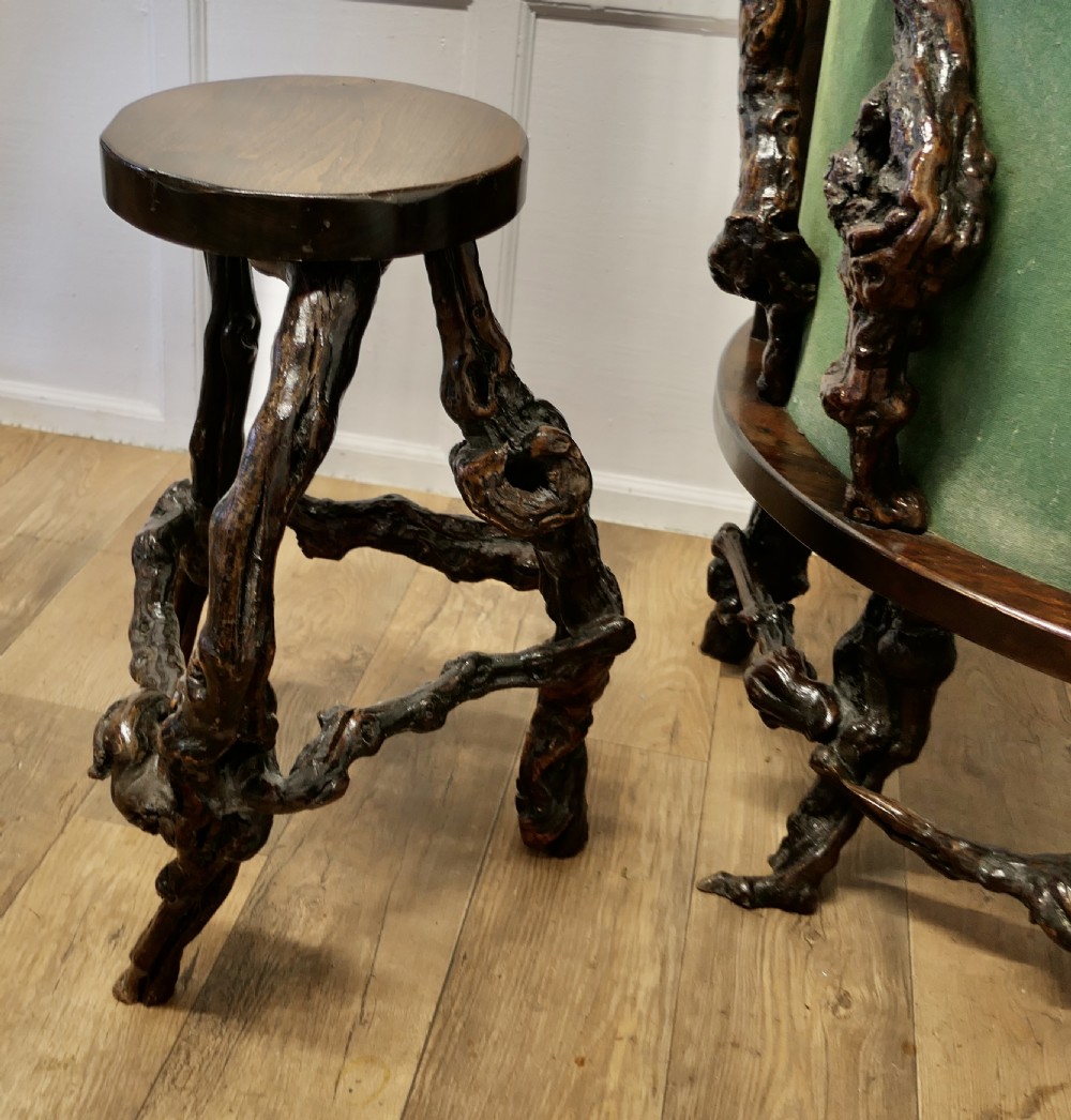 A curved home bar constructed from gnarled grapevine roots with a green padded front, accompanied by two matching round-topped bar stools. View III