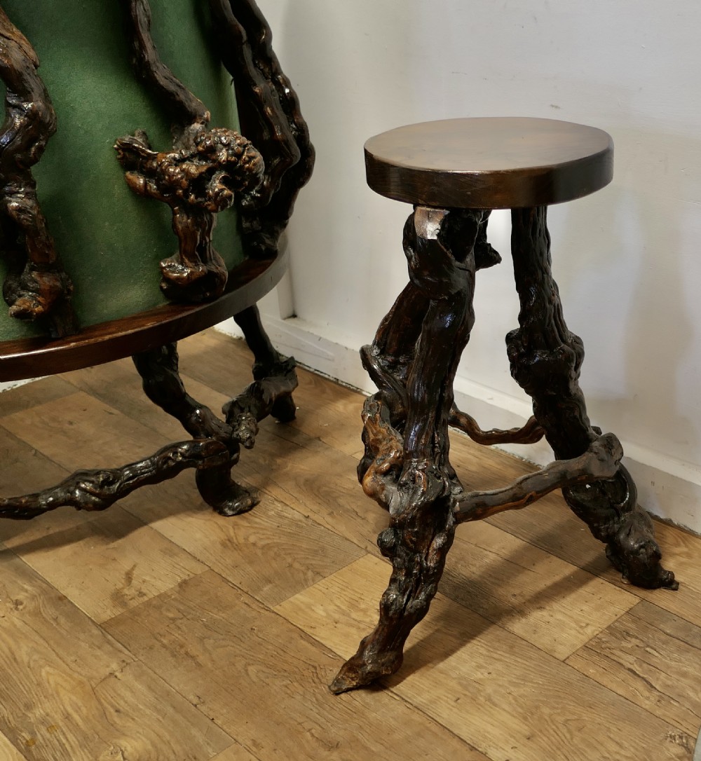 A curved home bar constructed from gnarled grapevine roots with a green padded front, accompanied by two matching round-topped bar stools. View IV