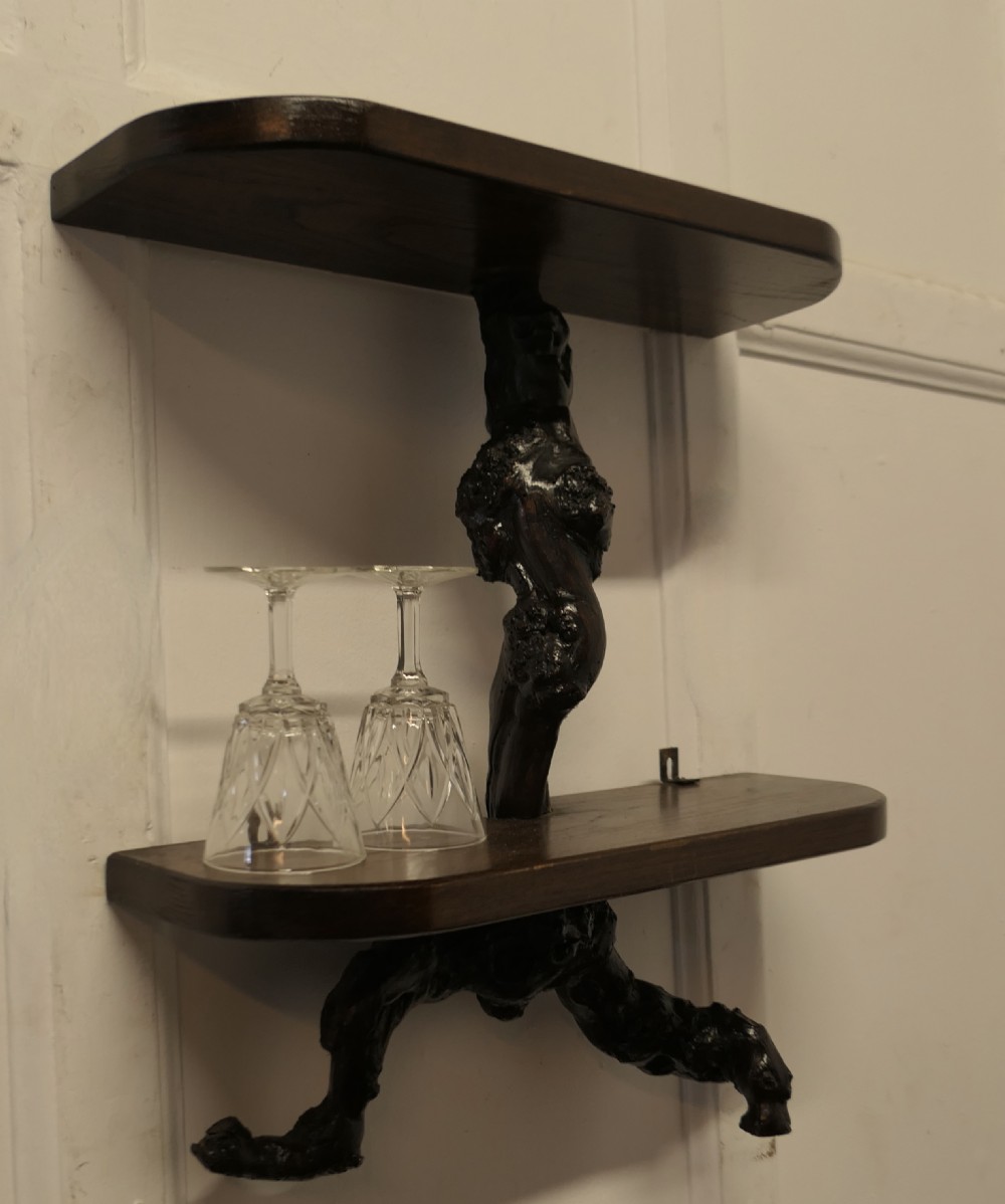 A curved home bar constructed from gnarled grapevine roots with a green padded front, accompanied by two matching round-topped bar stools. View VI