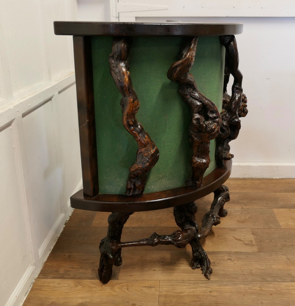 A curved home bar constructed from gnarled grapevine roots with a green padded front, accompanied by two matching round-topped bar stools. View VIII