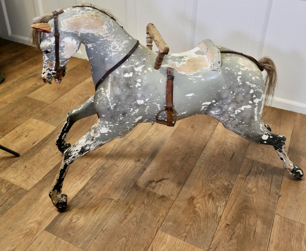 An early 19th-century hand-carved wooden horse featuring a distressed grey and white painted finish with leather harness and horsehair detail. View V