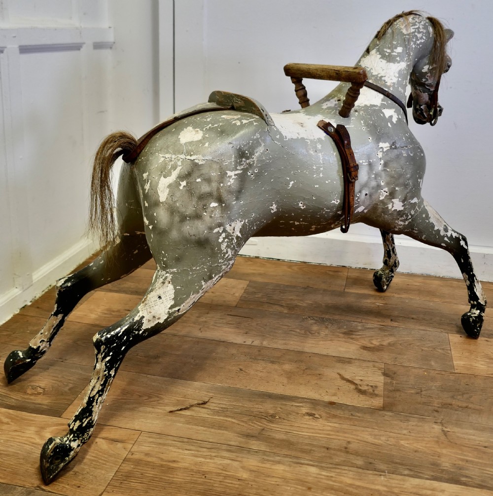 An early 19th-century hand-carved wooden horse featuring a distressed grey and white painted finish with leather harness and horsehair detail. View VI