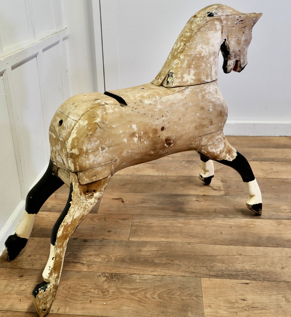 A large carved pine rocking horse figure with a heavily distressed off-white and black painted finish, detached from its original rocker base.