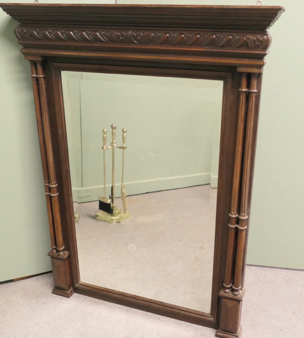 A dark oak rectangular wall mirror featuring an architectural carved cornice and twin slender columns flanking the glass plate. View V