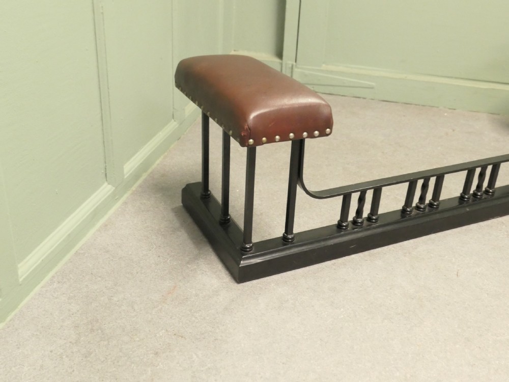 An Art Deco style club fender featuring a black iron frame with twisted vertical spindles and two elevated tan leather padded seats trimmed with studs. View III