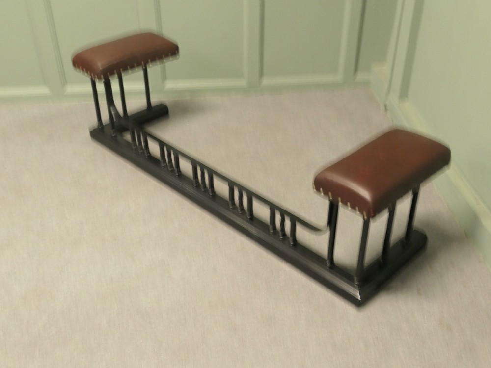 An Art Deco style club fender featuring a black iron frame with twisted vertical spindles and two elevated tan leather padded seats trimmed with studs. View VI