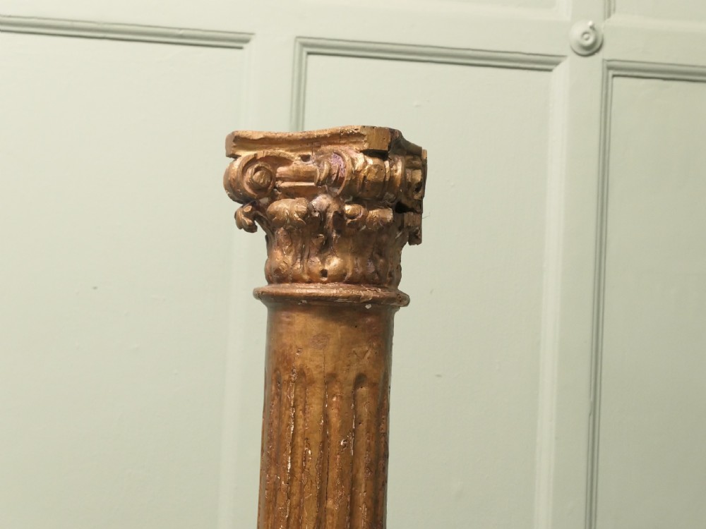 A tall, carved giltwood Corinthian column pedestal featuring a fluted shaft, acanthus leaf capital, and decorative base. View V