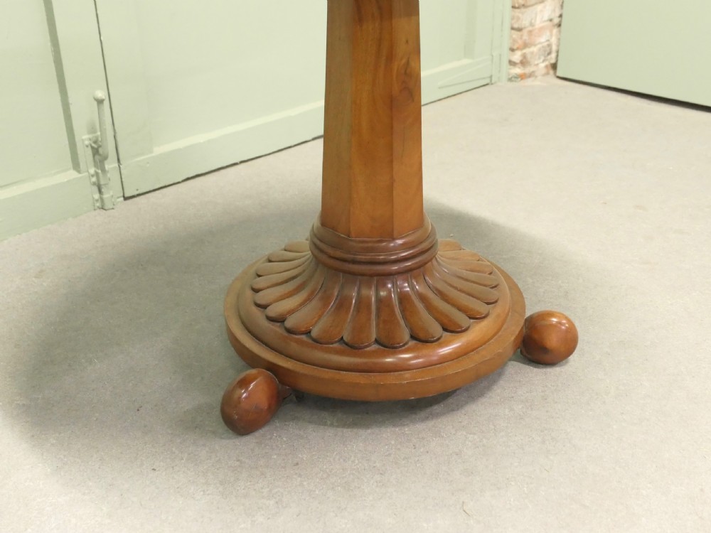 A circular cherrywood centre table featuring a polished tilt-top surface, a central stem, and a carved petal-form pedestal base on ball feet. View V