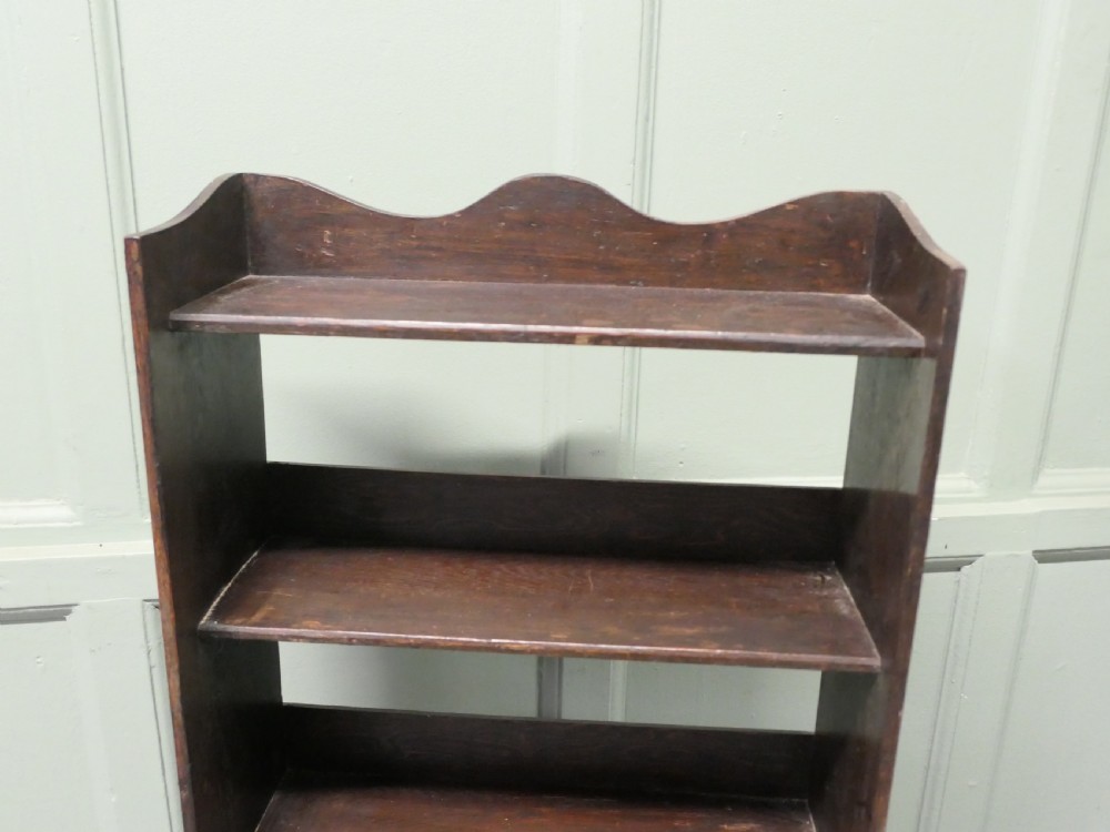 A tall dark wood Art Deco open bookcase featuring five shelves, a scalloped top rail, and a solid plinth base. View VI