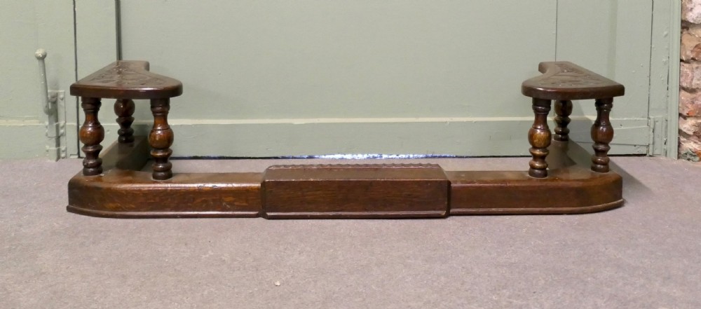 An Arts and Crafts carved oak adjustable club fender with turned baluster supports and decorative corner seats. View II