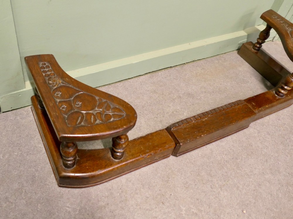 An Arts and Crafts carved oak adjustable club fender with turned baluster supports and decorative corner seats. View V