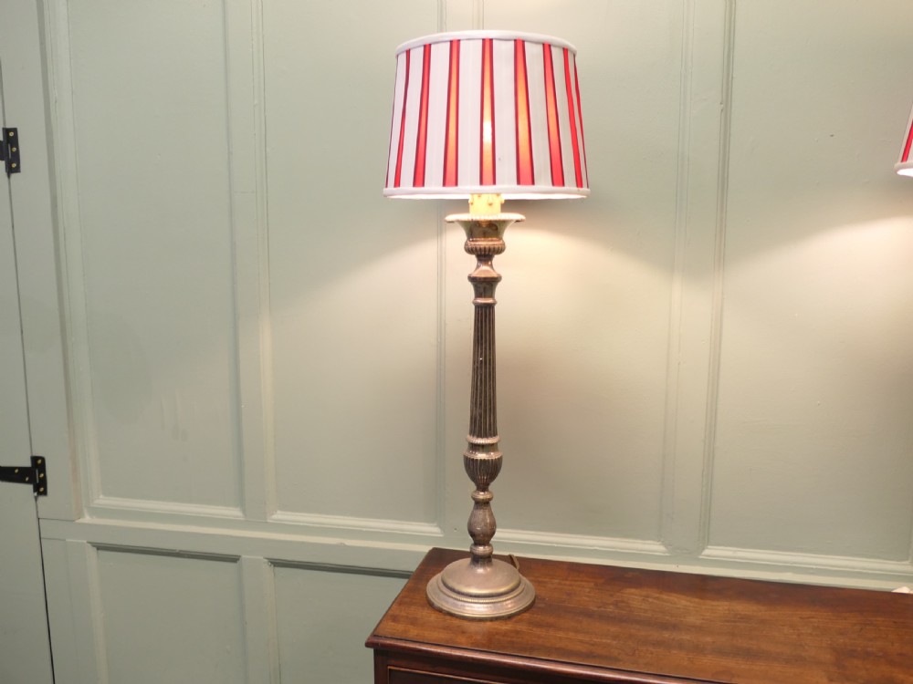 A pair of tall silver plated candlestick table lamps featuring reeded column stems and red and white striped shades. View III