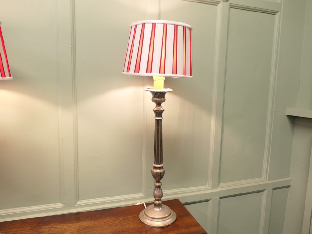 A pair of tall silver plated candlestick table lamps featuring reeded column stems and red and white striped shades. View IV