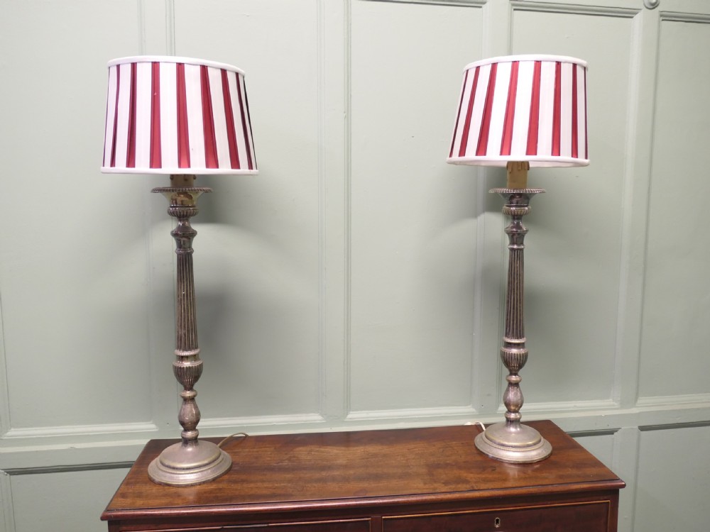 A pair of tall silver plated candlestick table lamps featuring reeded column stems and red and white striped shades. View V