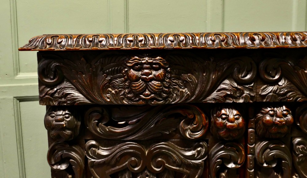 A dark brown oak cupboard featuring two doors adorned with detailed foliate and mask relief carvings. View II