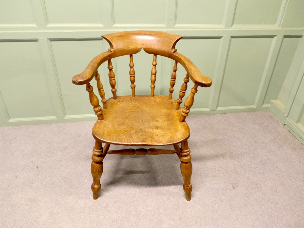 A 19th-century smokers bow armchair made from beech and elm with turned spindles and a contoured saddle seat. View II