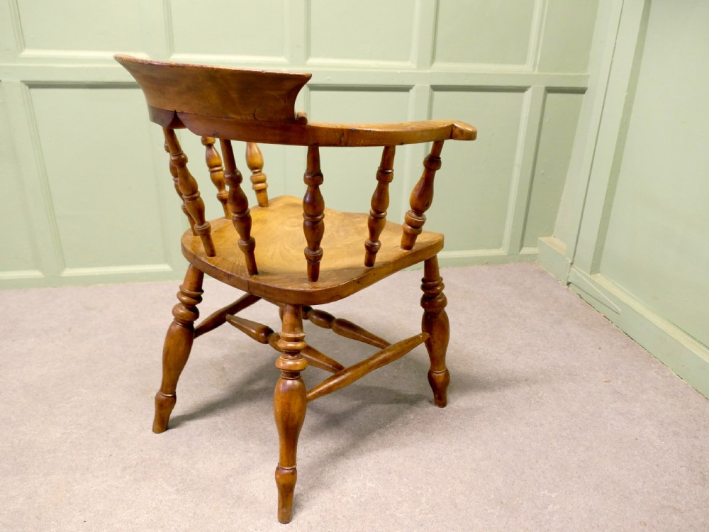 A 19th-century smokers bow armchair made from beech and elm with turned spindles and a contoured saddle seat. View VII