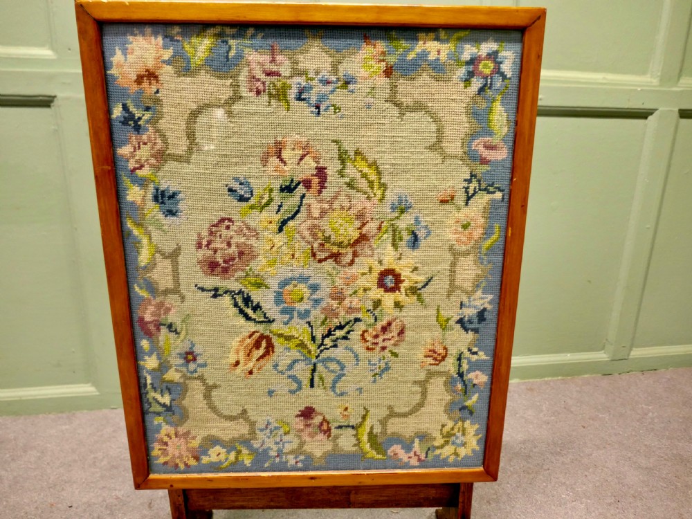 An antique wooden metamorphic fire screen with a framed floral embroidery panel standing on splayed feet. View IV